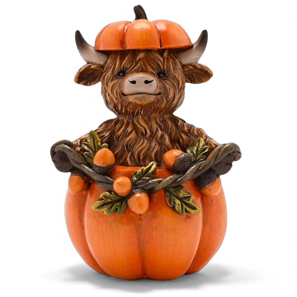 Decorative Highland cow figurine sitting in an orange pumpkin with an orange hat and leaves