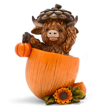 Decorative Highland cow figurine in an orange pumpkin planter with a sunflower at the base