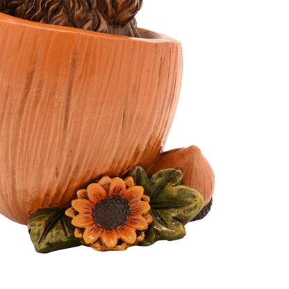 Decorative cow figurine with an orange pumpkin planter and sunflower-style flower decoration