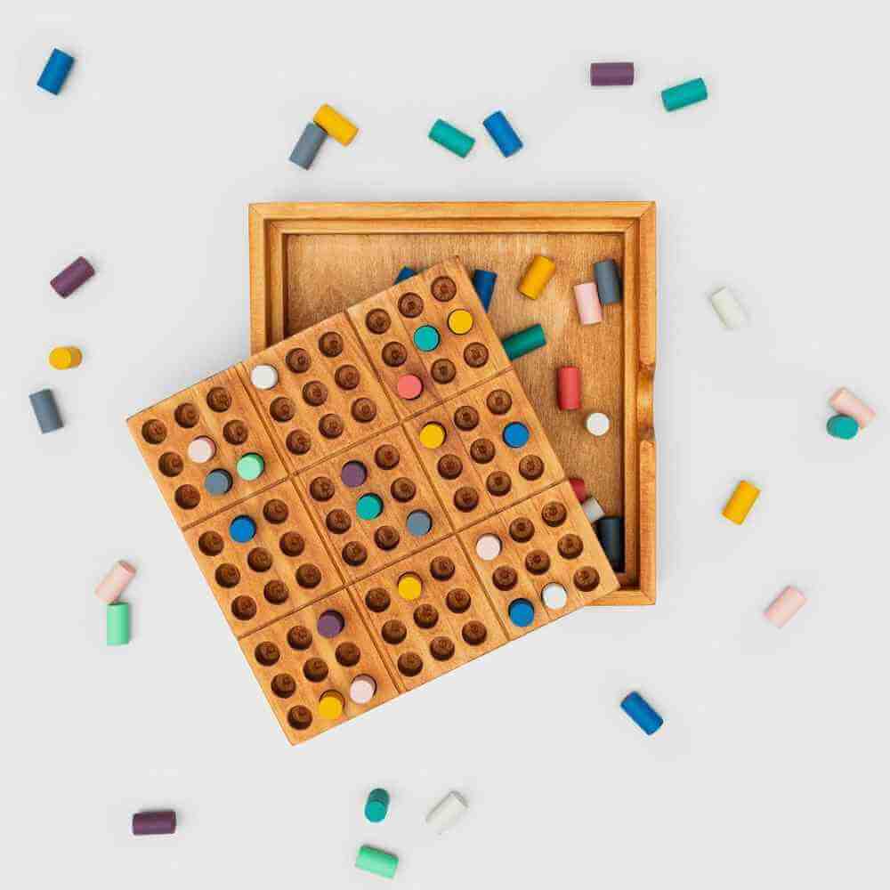 Wooden colour sudoku game board with colored pegs and open storage tray