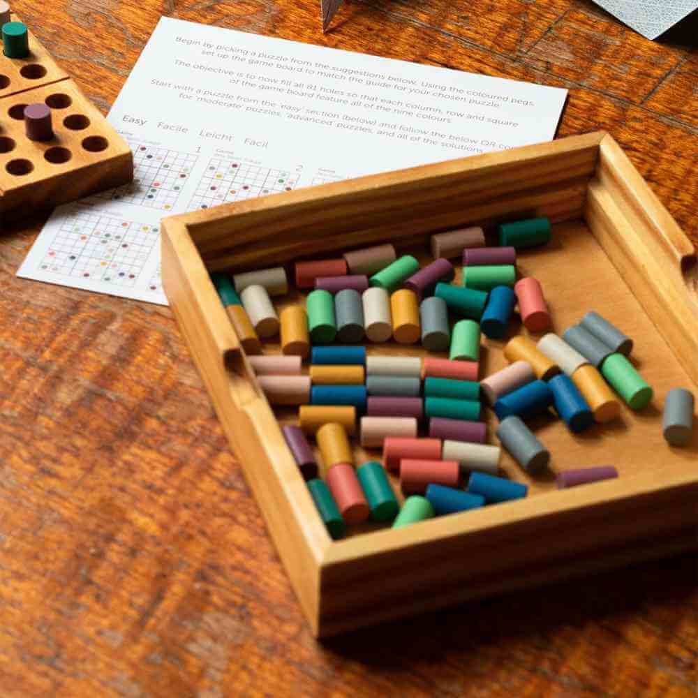 Wooden colour sudoku game base with compartment filled with multi-color wooden pegs