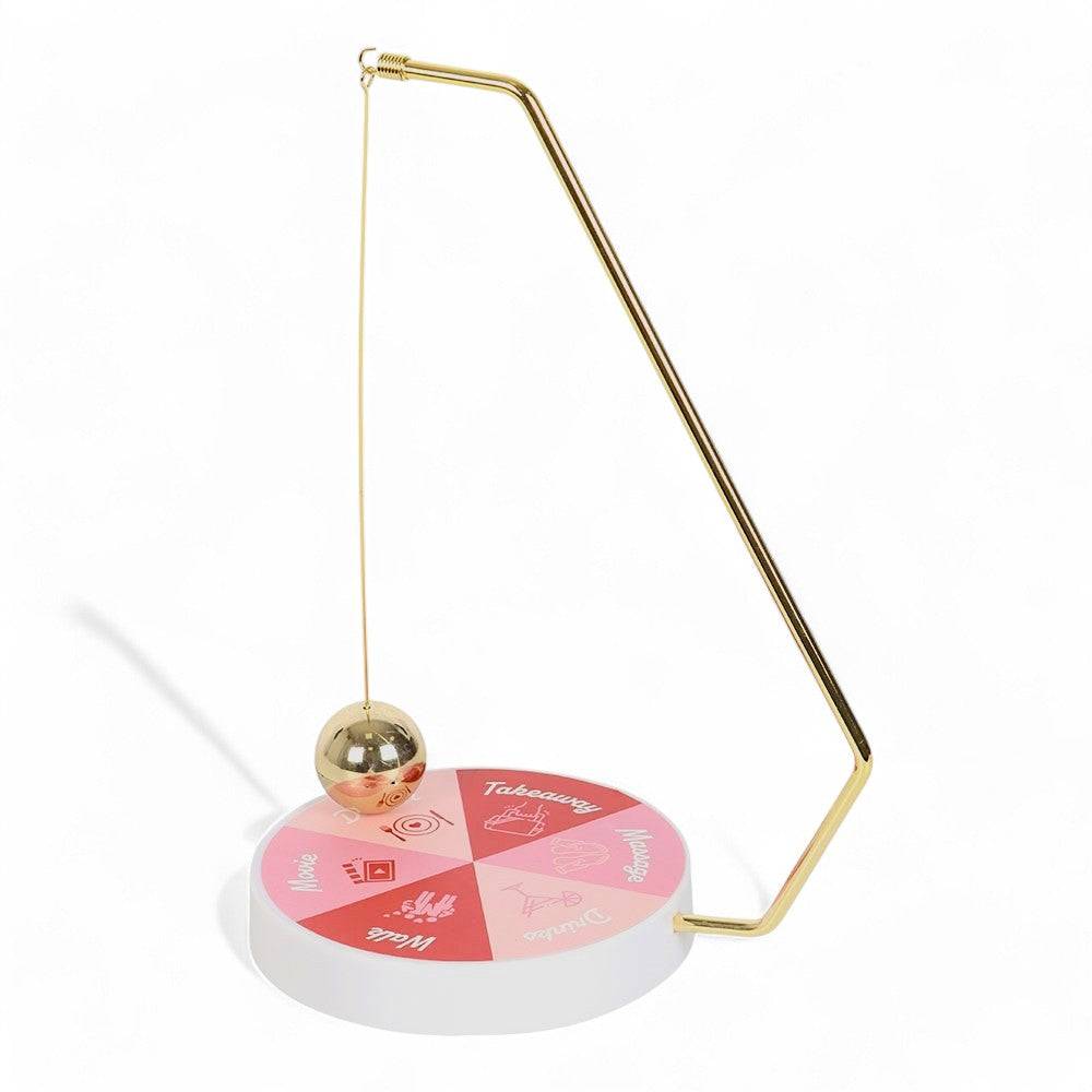Gold pendulum stand with hanging ball and round labeled game wheel