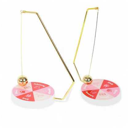 Two gold pendulum stands with hanging balls and round game wheels