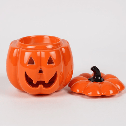 Orange jack-o-lantern oil burner with lid off, showing black stem pieces