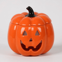 Orange jack-o-lantern oil burner with black stem and carved smiling face cutouts