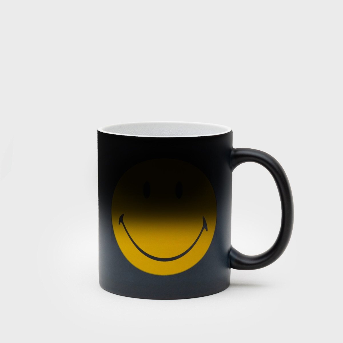 Black ceramic mug with yellow smiley face graphic visible on the front