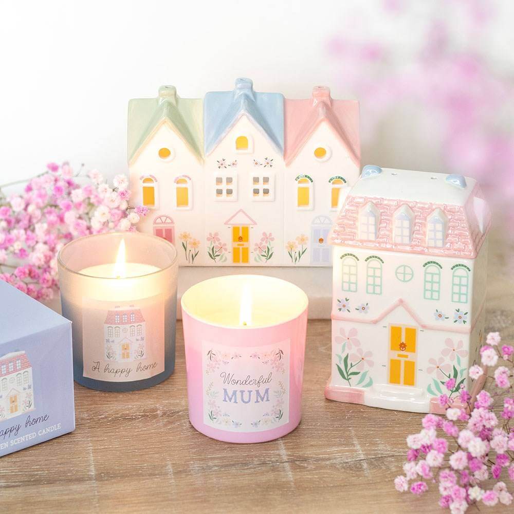 Pink scented candle with 'Wonderful Mum' label beside illustrated house-style gift boxes