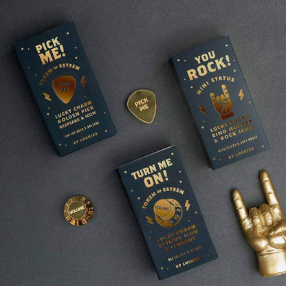 Gold rock-on hand ring holder with mini statue cards on a dark desk