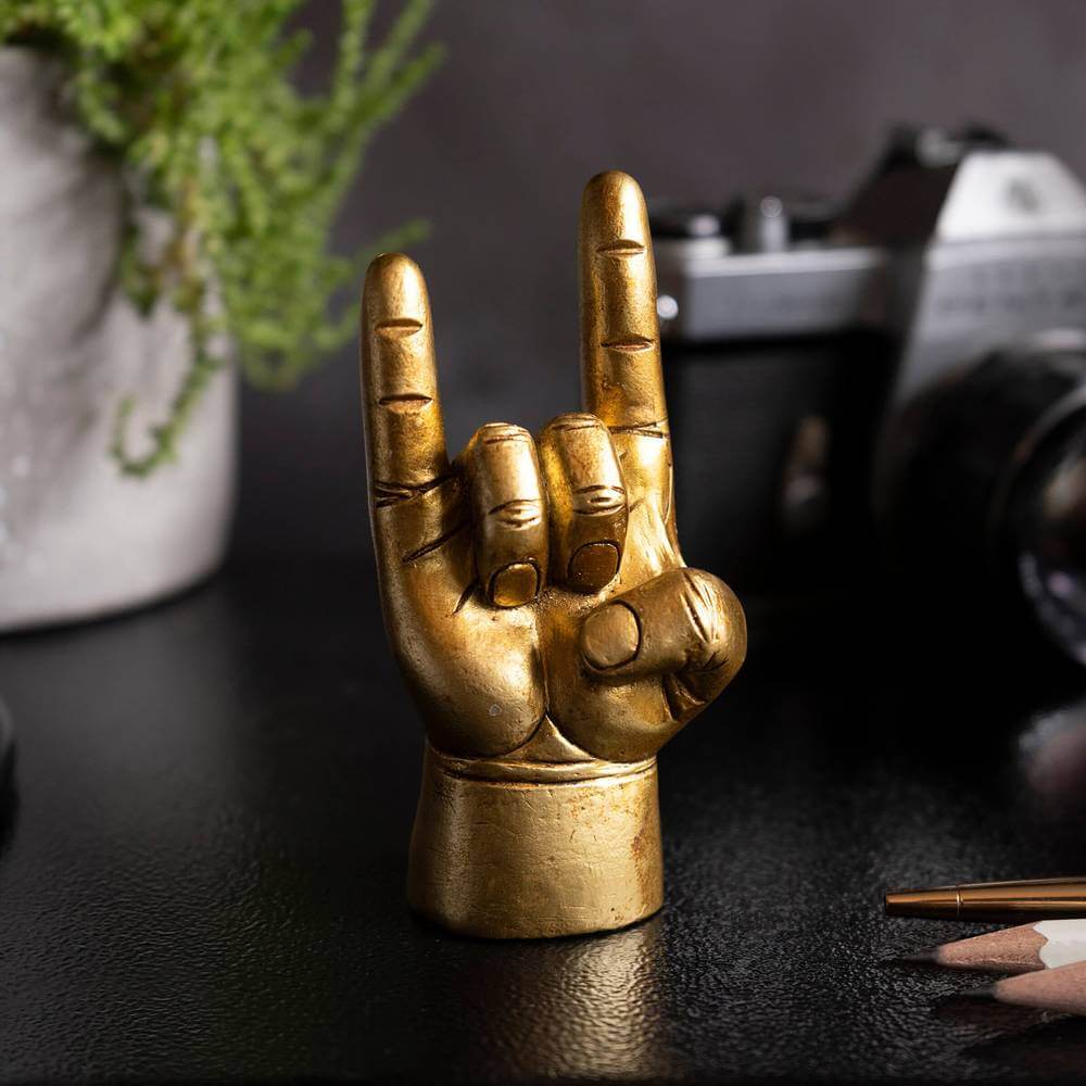 Gold rock-on hand ring holder statue on a desk surface