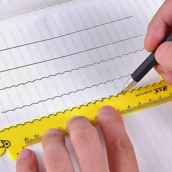 Yellow animal-shaped kids ruler with scalloped edge and measurement marks on paper