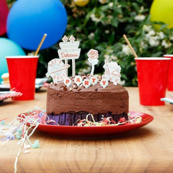 Cake topper decorations set with 'PARTY' cutout pieces on a chocolate cake