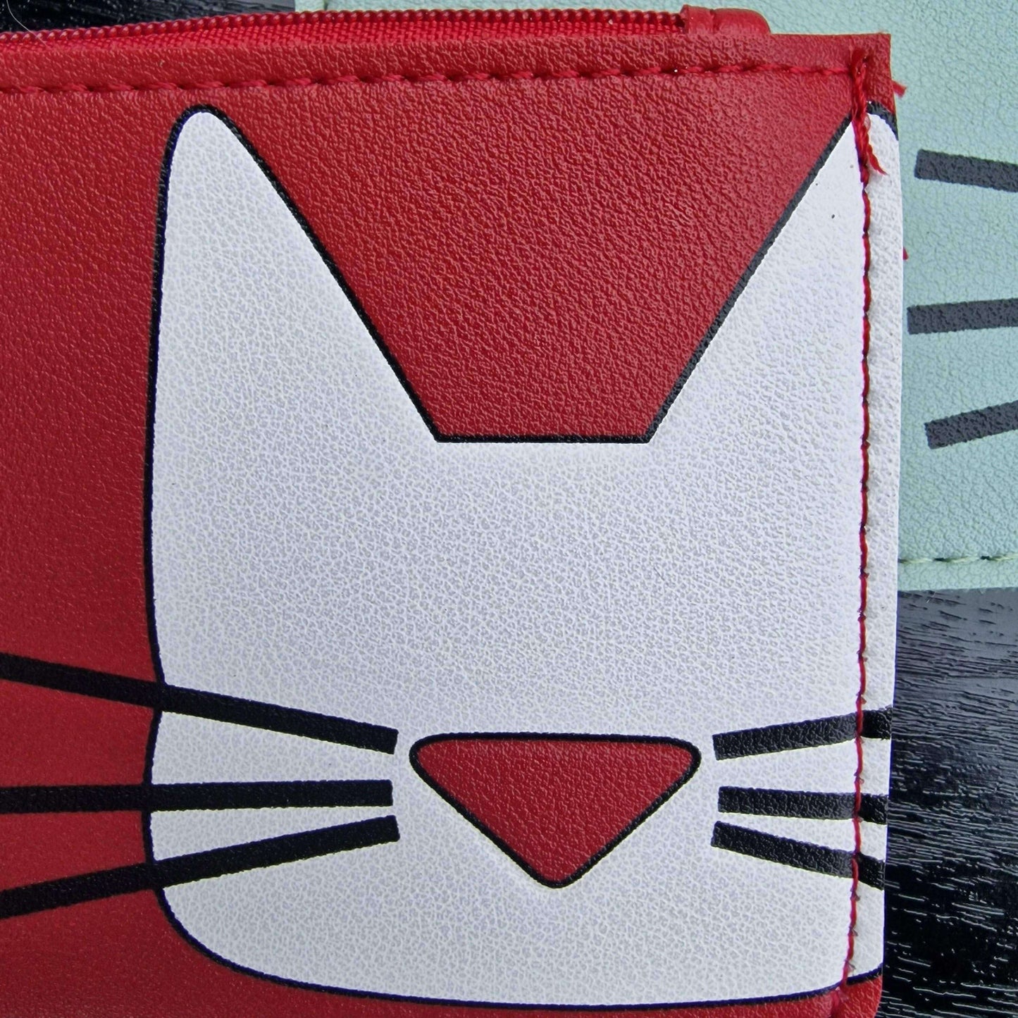 Red faux leather card pouch with white cat face graphic and zipper edge