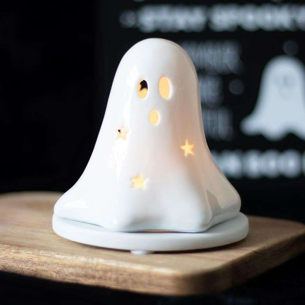 White ceramic ghost tealight holder with painted orange face details and gold star accents