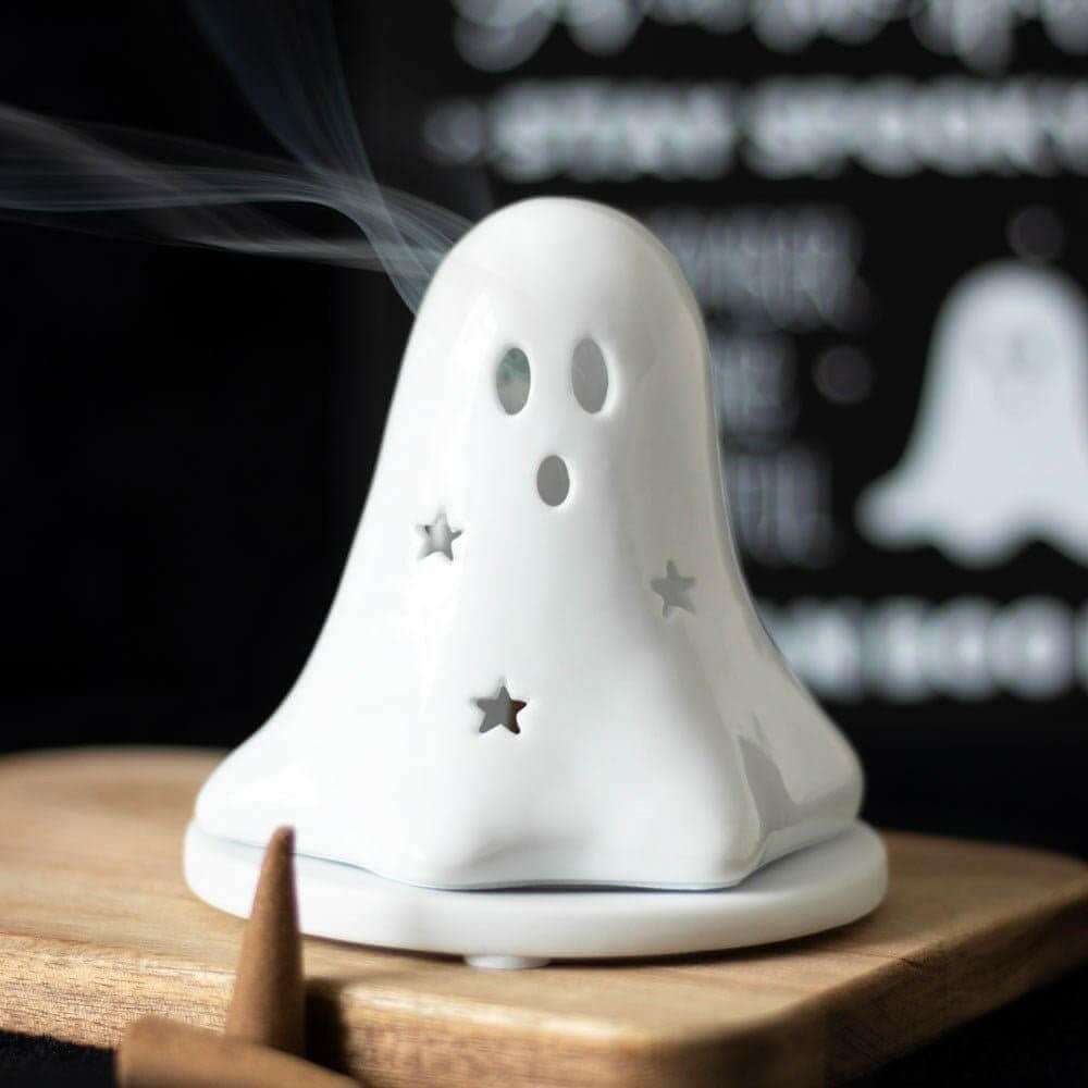 White ceramic ghost tealight holder with hollow face holes, gold stars, and incense smoke