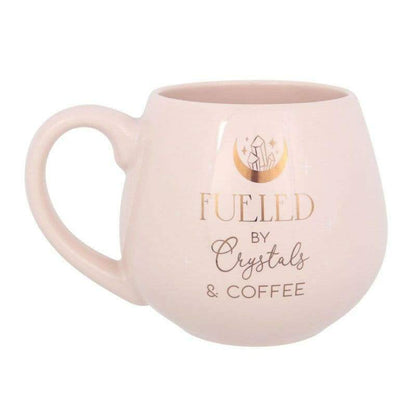 Pink rounded mug with 'FUELED by Crystals & COFFEE' text, side view