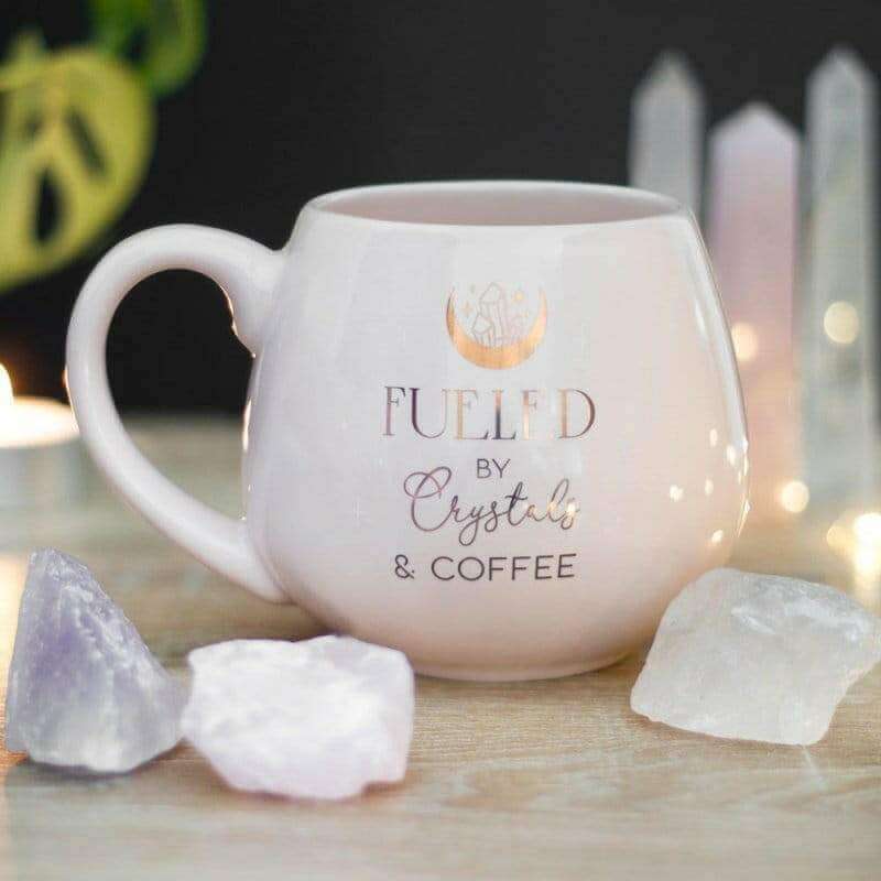 Pink rounded mug with 'FUELED by Crystals & COFFEE' text and logo