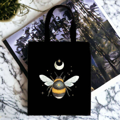 Black cotton tote bag with moon-and-bee graphic, long handles