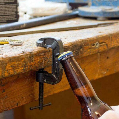 G-Clamp bottle opener clamping a brown glass bottle on a wooden beam