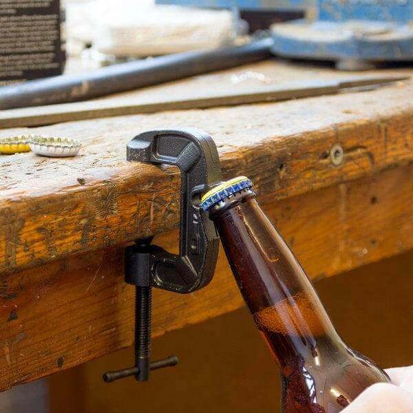 G-Clamp bottle opener clamped to a wooden beam, holding a brown glass bottle