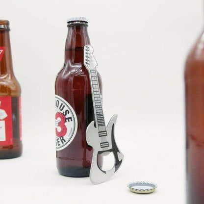 Stainless steel guitar bottle opener with lift end, next to brown beer bottle.
