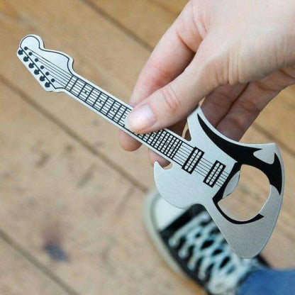 Guitar-shaped bottle opener held between fingers over a tabletop