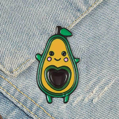 Avocado enamel pin badge on denim, smiling face with green outline and dark heart