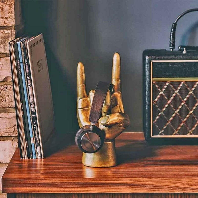 Rock On headphone stand with upright golden hand and black over-ear headphones