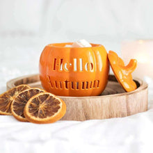 Orange pumpkin wax melt burner with carved text, open lid, wood tray and citrus slices