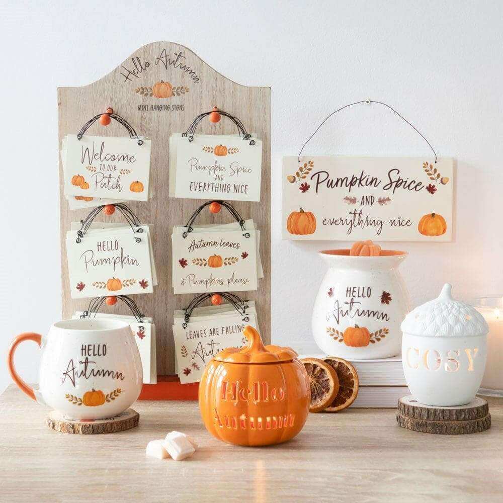 Orange pumpkin wax melt burner on round wood base with wax candle set