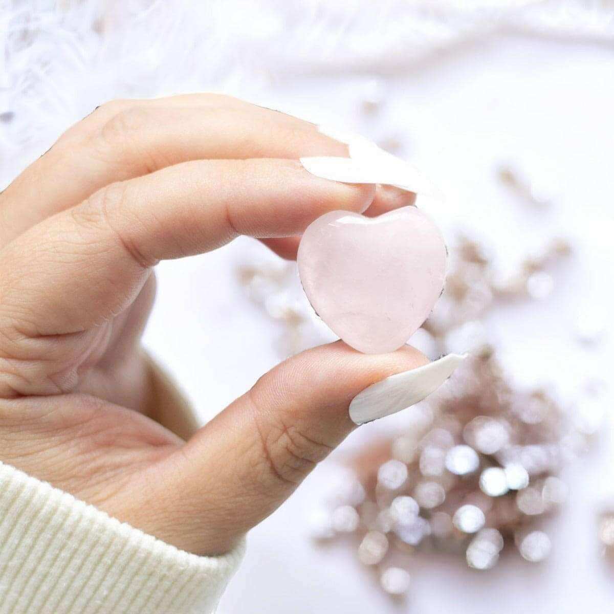 Pink rose quartz heart in hand with small heart-like crystal pieces