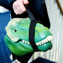 Green T-rex lunch box with black carry strap, held by a hand