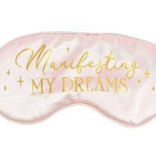 Satin sleep eye mask close-up with “Manifesting My Dreams” gold script and stars