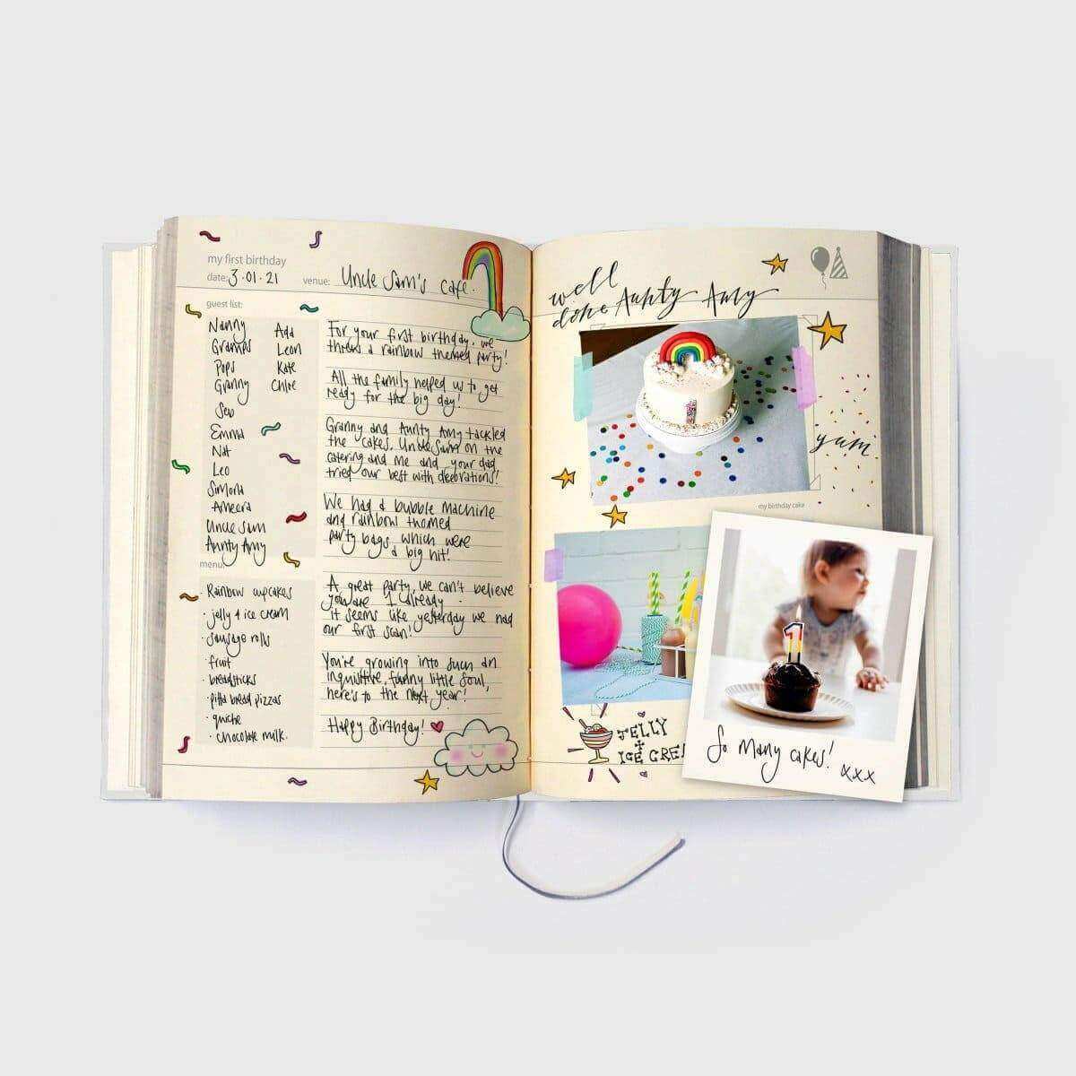 Baby years journal open to handwritten-style pages with baby photo and decorated cake image