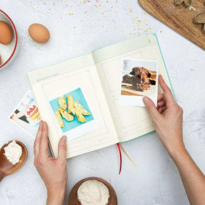 Open baking journal book with photos and ingredient guide pages, held by hands