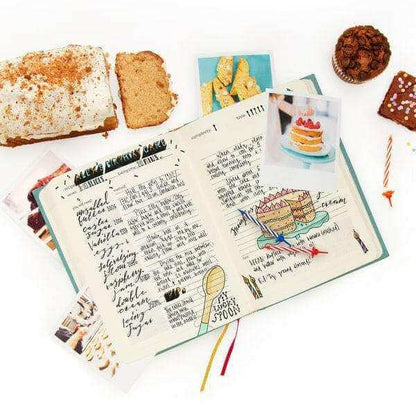 Open baking journal book with handwritten recipe notes, cake images, and diagrams