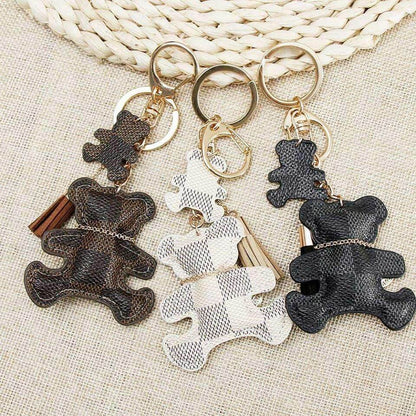 Patchwork teddy bear keyring set on woven fabric with gold rings, tassels, and coin charms