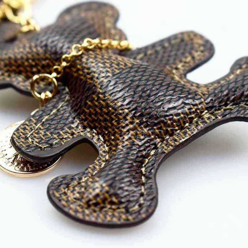 Close-up patchwork teddy bear keyring with woven dark brown texture and gold chain