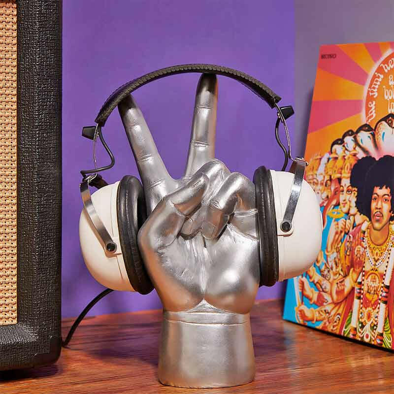 Metallic hand-shaped headphone stand holding black over-ear headphones