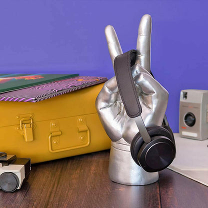 Metallic hand-shaped headphone stand with black headphones and strap