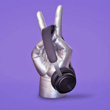 Metallic hand-shaped headphone stand with black strap and headband