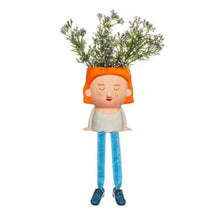 Plant mum planter figure with orange hair and dangling legs, holding a small green plant