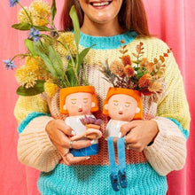 Plant mum planter with dangling legs, orange hair lady, holding a small flower pot