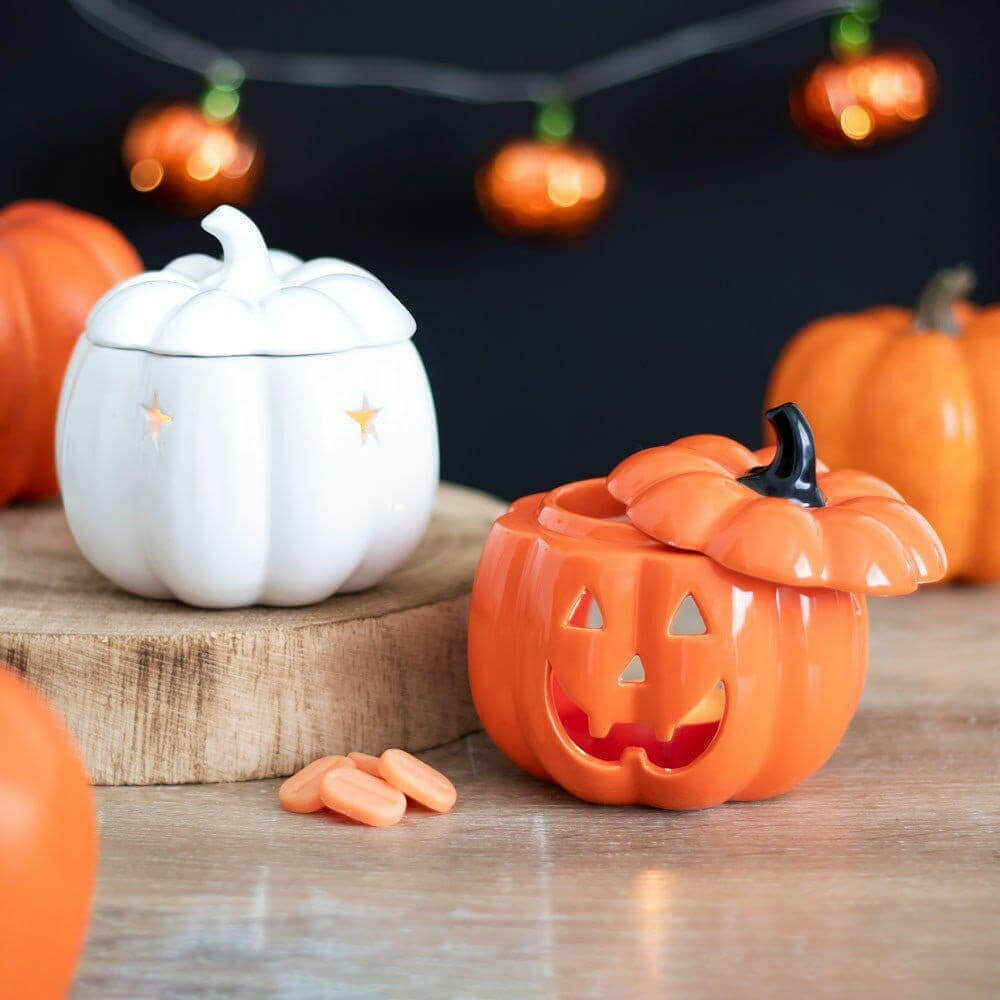 Orange jack-o-lantern wax melt warmer with carved face and black hinged lid