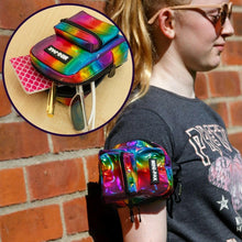 Rainbow metallic mini backpack with front zip pocket and black arm strap on wrist.