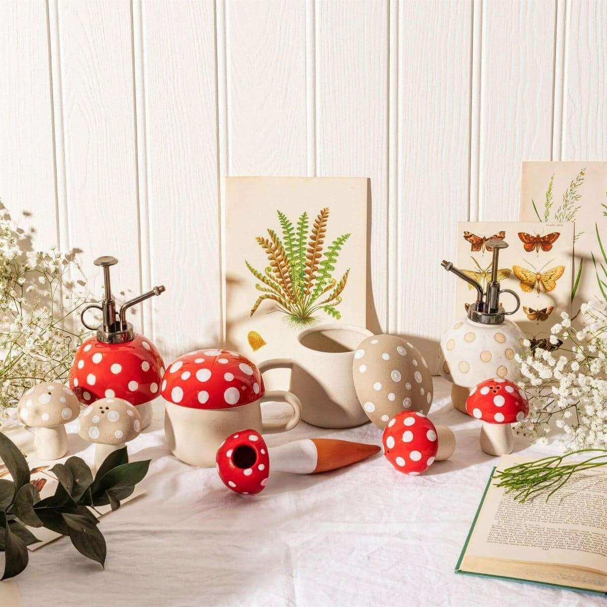 Mushroom plant mister with red-and-white dotted cap, black stem pump, and white base