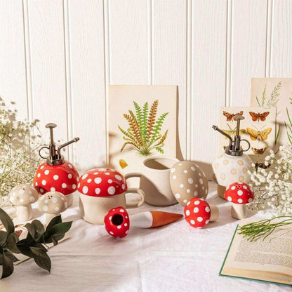 Mushroom plant mister with red-and-white dotted cap, black stem pump, and white base