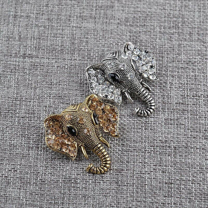 Silver elephant crystal brooch and gold elephant crystal brooch on textured fabric