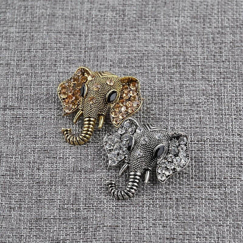 Gold and silver elephant crystal brooches on textured fabric