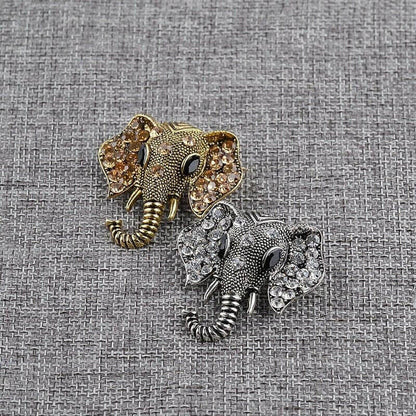 Gold and silver elephant crystal brooches on textured fabric
