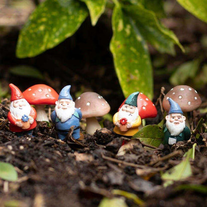Mini gnome plant pot pals figurines with mushroom tops in garden soil and leaves